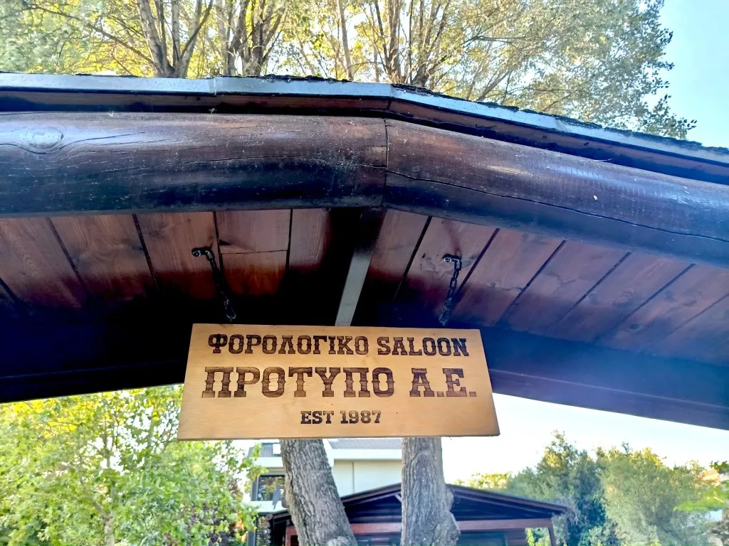 Η ξύλινη ταμπέλα «Φορολογικό Saloon – Πρότυπο Α.Ε.» στην είσοδο του γραφείου στο Κρυονέρι